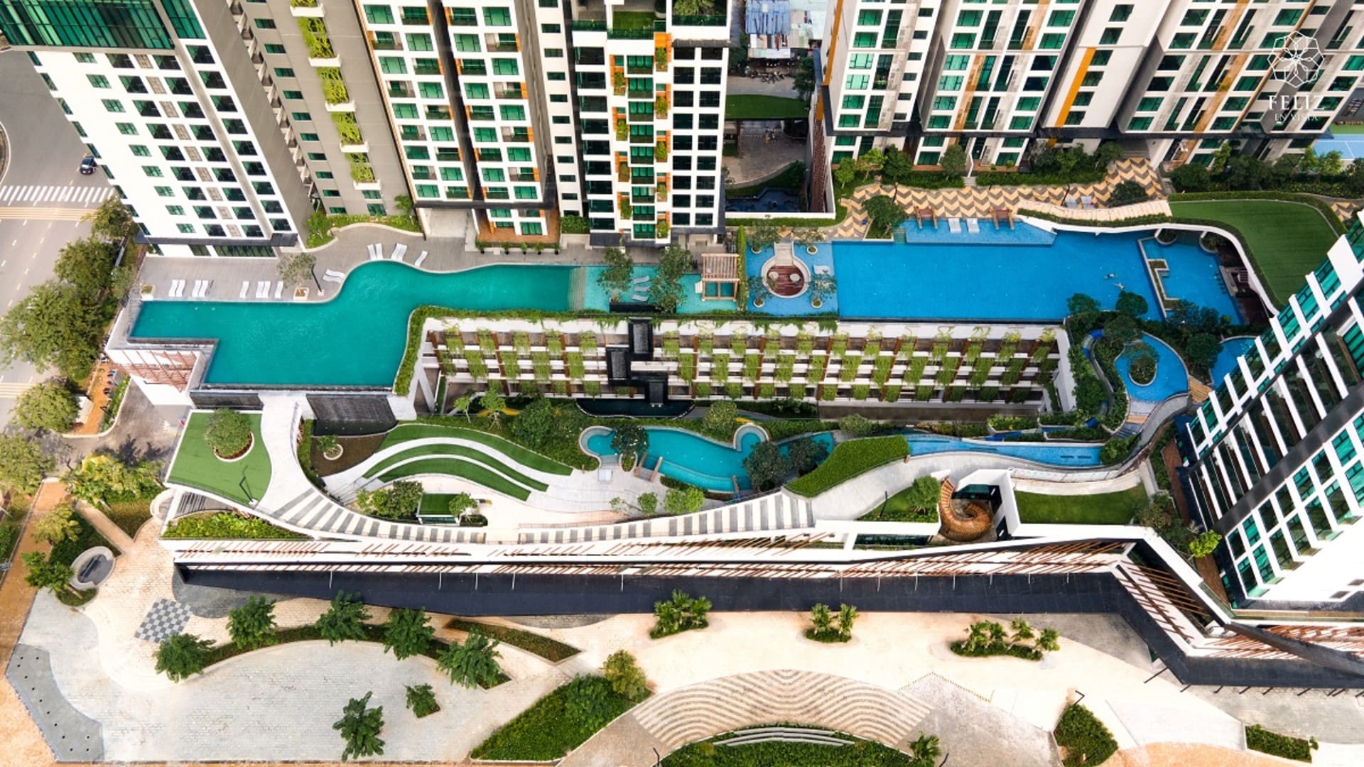 Góc nhìn từ trên cao tại Feliz En Vista Quận 2 cho thấy hệ thống hồ bơi, sân vườn và đường dạo được sắp xếp giữa các tòa căn hộ, kết hợp nhiều mảng xanh trong không gian tiện ích nội khu.