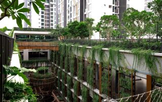 Không gian cảnh quan tại Feliz En Vista Quận 2 nổi bật với cây xanh tán rộng, dây leo phủ theo các tầng công trình và lối đi giữa vườn, đưa mảng xanh đến gần không gian sinh hoạt nội khu.