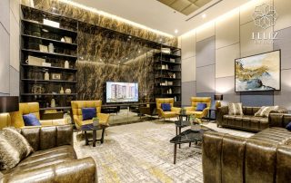 Phòng tiếp khách tại Feliz En Vista Quận 2 được bài trí với sofa da nâu, ghế bành vàng, bàn trà và vách đá trang trí, tạo nên không gian gặp gỡ lịch sự trong khu tiện ích nội khu.